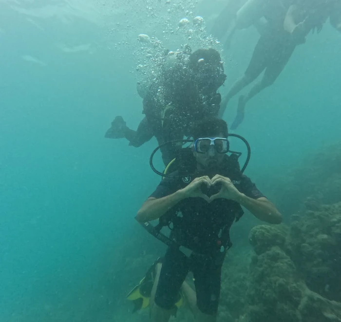 Diver making a heart shape with the guide behind