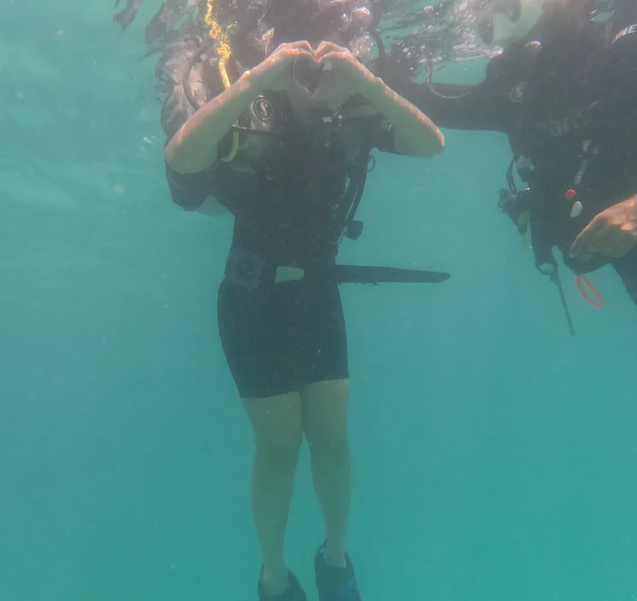 Diver making a heart shape above her head while diving in Havelock Island