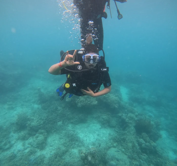 Diver making a heart shape above the sandy bottom