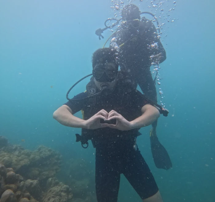 Diver making a heart shape underwater with the guide behind