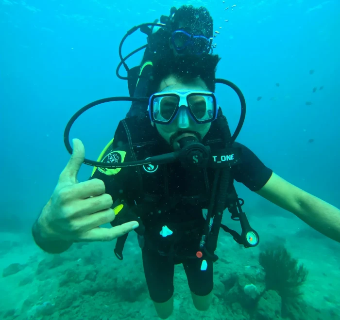 Diver making a shaka sign towards the camera on a shallow dive