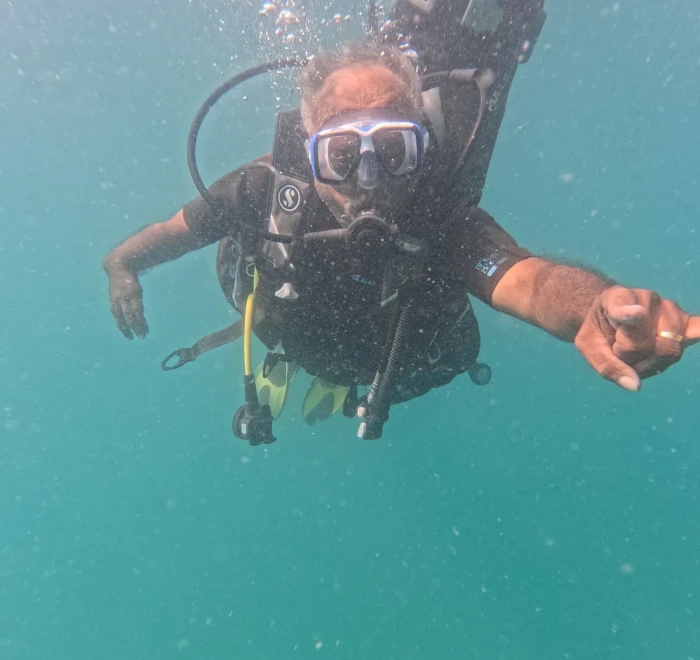 Diver reaching towards the camera above the reef while scuba diving in Havelock
