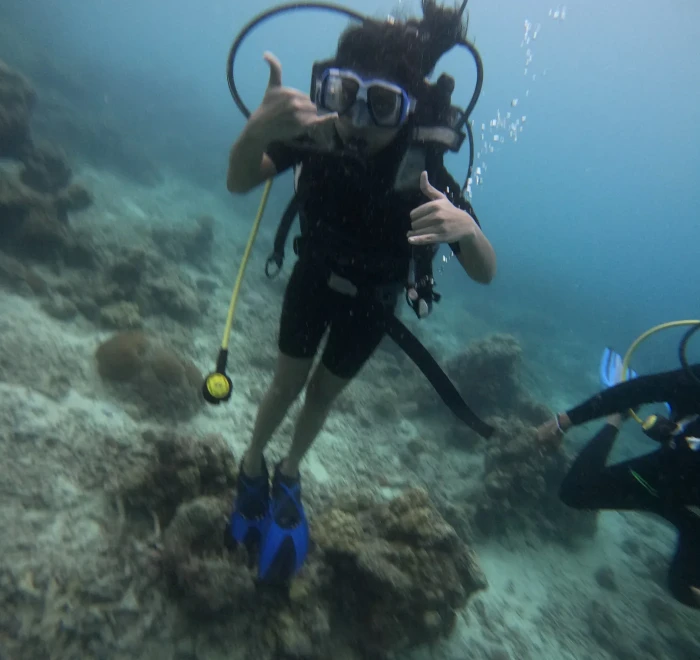 Diver signalling to the camera above the reef