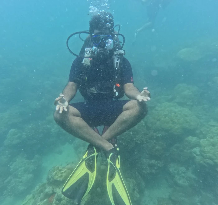 Diver sitting cross-legged above the reef