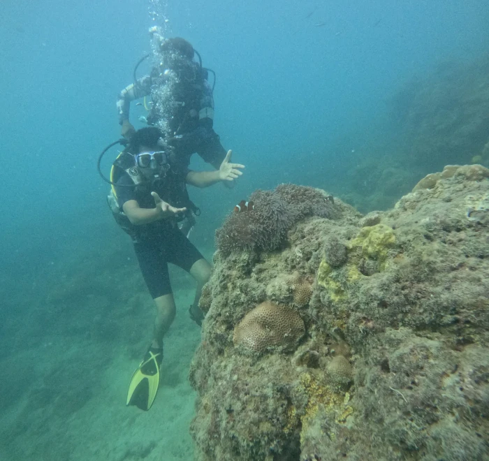 Diver swimming over a rocky section of reef in the Andaman Sea