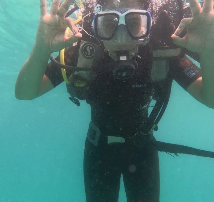 Diver waving both hands towards the camera underwater