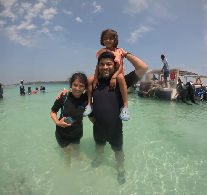 Family in the shallows at Havelock with the dive boats behind