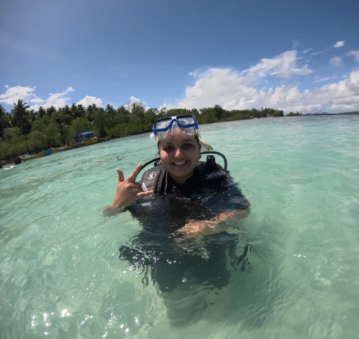 Guest giving a peace sign in the shallows before a shore dive