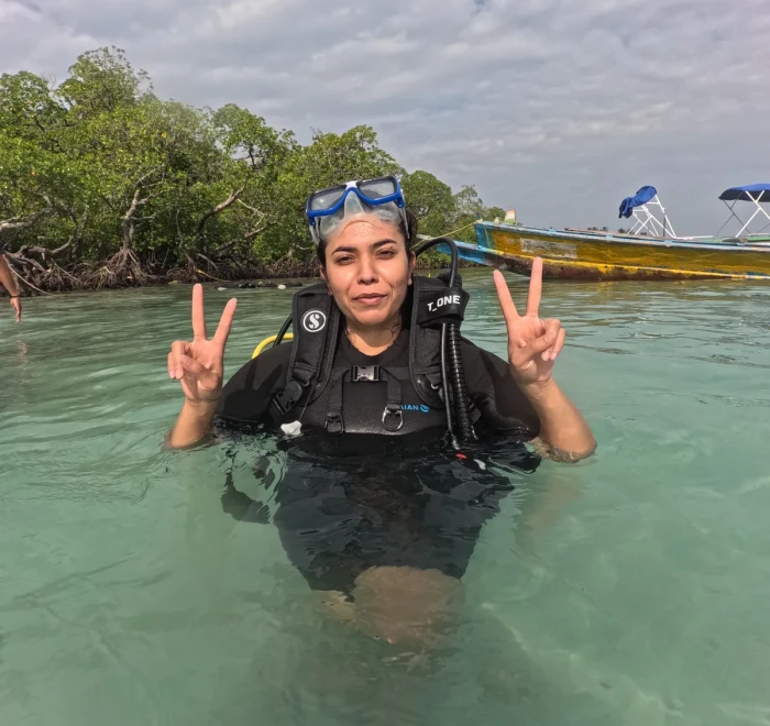 Guest giving peace signs in the shallows before her dive
