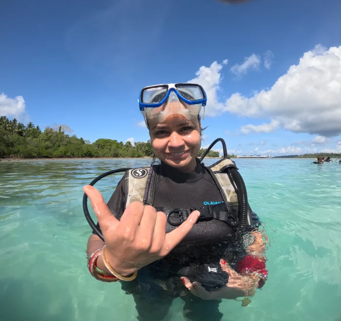 Guest in mask and scuba gear giving a shaka sign in the shallows