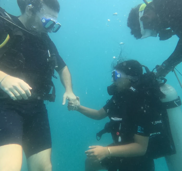Instructor holding a first-time diver's hand through their first minutes underwater