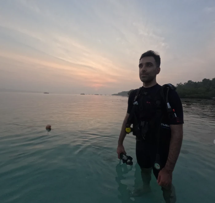 Instructor standing in calm water at sunset after the last dive of the day