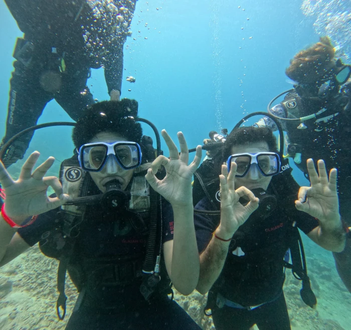 Two divers giving the OK signal to the camera on a guided dive