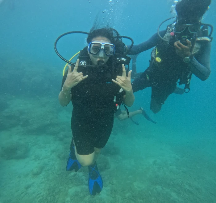 Two divers giving peace signs underwater