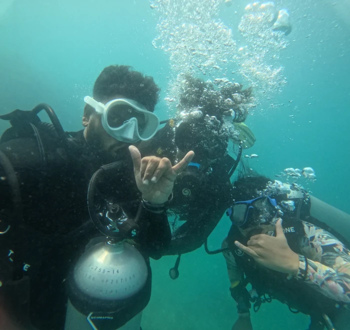 Two divers giving shaka signs to the camera underwater