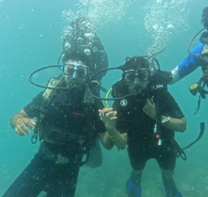 Two divers close together giving thumbs up