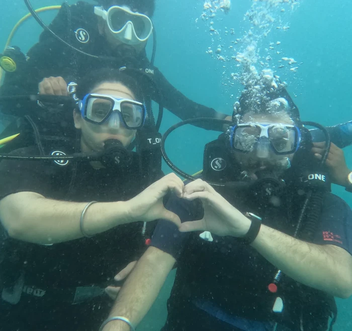 Two divers making a heart shape with their hands while scuba diving in Havelock