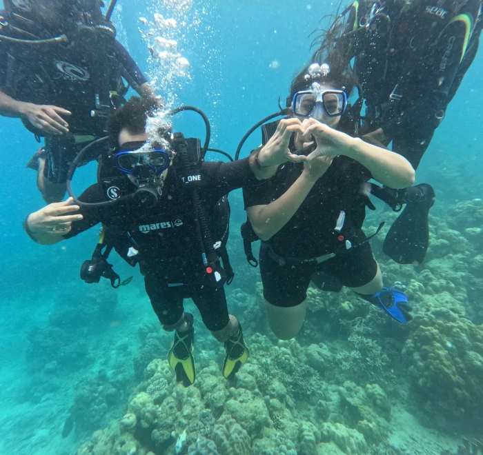 Two divers making a heart shape together underwater