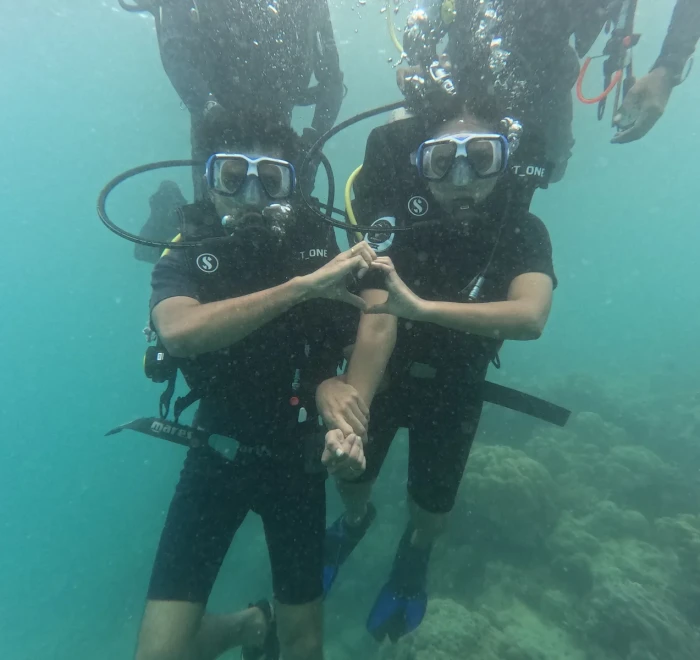 Two divers making a heart shape underwater at the end of their dive