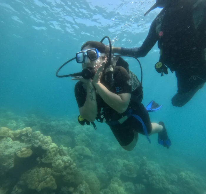 Two divers moving along the reef in green water
