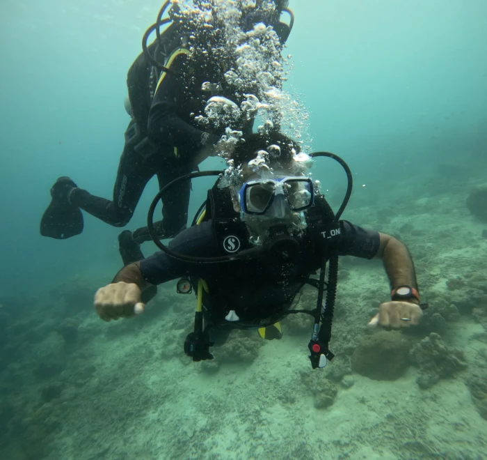 Two divers above the sandy bottom close to the camera