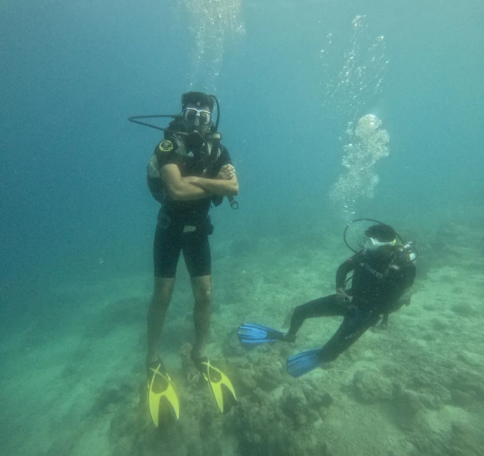 Two divers above the sandy bottom in shallow water