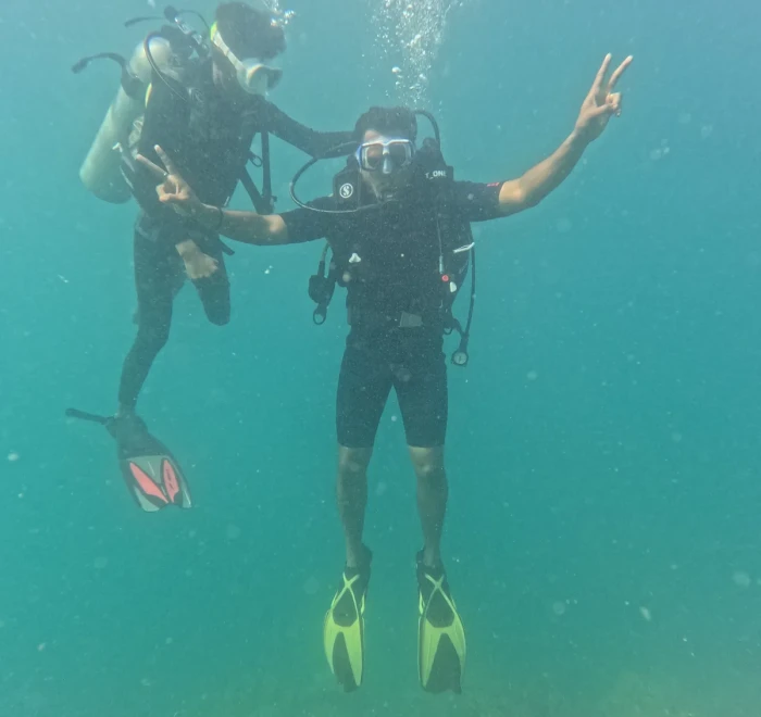 Two divers side by side giving peace signs