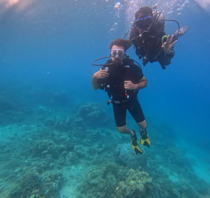Two divers together underwater above the reef in clear water