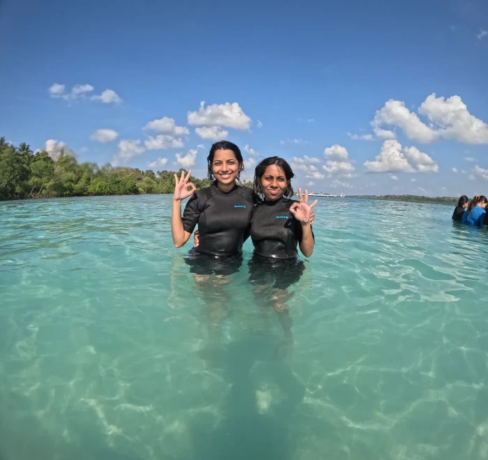 Two guests giving OK signs in the shallows at Havelock