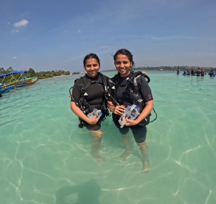 Two guests in scuba gear standing in the shallows at Havelock
