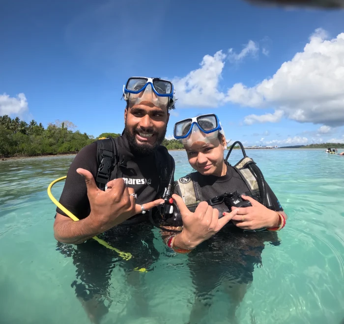 Two guests in the shallows giving shaka signs before their dive