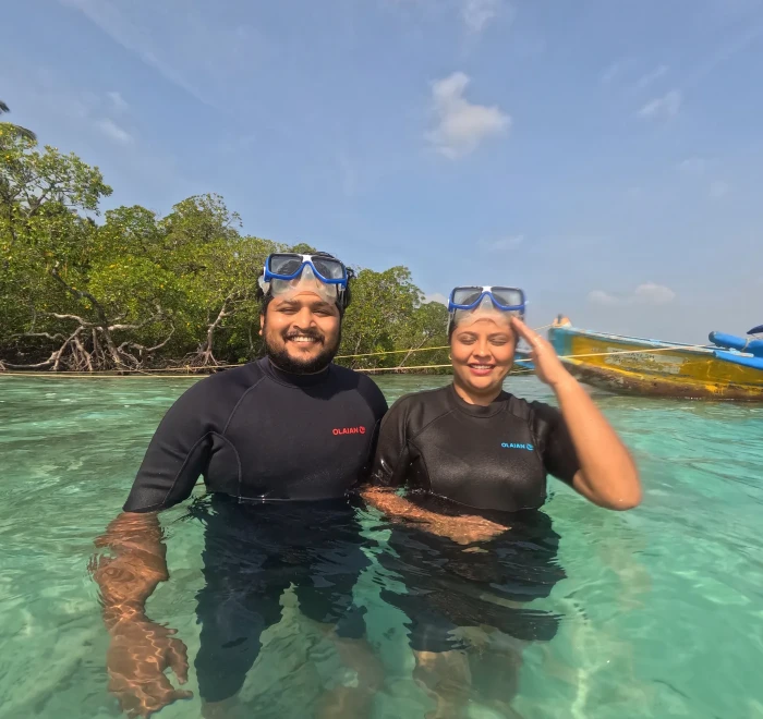 Two guests in wetsuits standing in the shallows before a shore dive