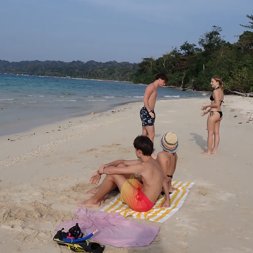 Guests relaxing on the empty white-sand beach at Cinque Island, Andaman