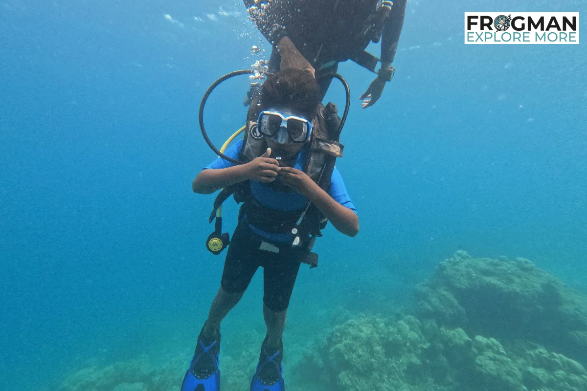 Young diver in a kids' size wetsuit, BCD and fins on a try scuba dive in Havelock with the instructor just above